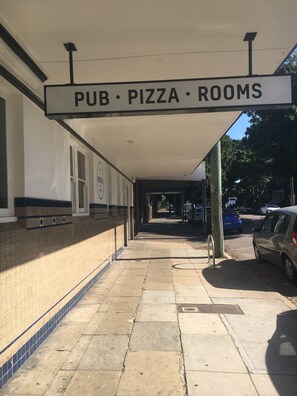 A covered walkway leading to a building with a sign reading "PUB • PIZZA • ROOMS".