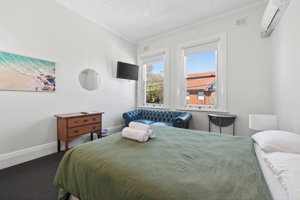 A hotel room with a bed, a desk, a chair, a TV, and a window with a view.