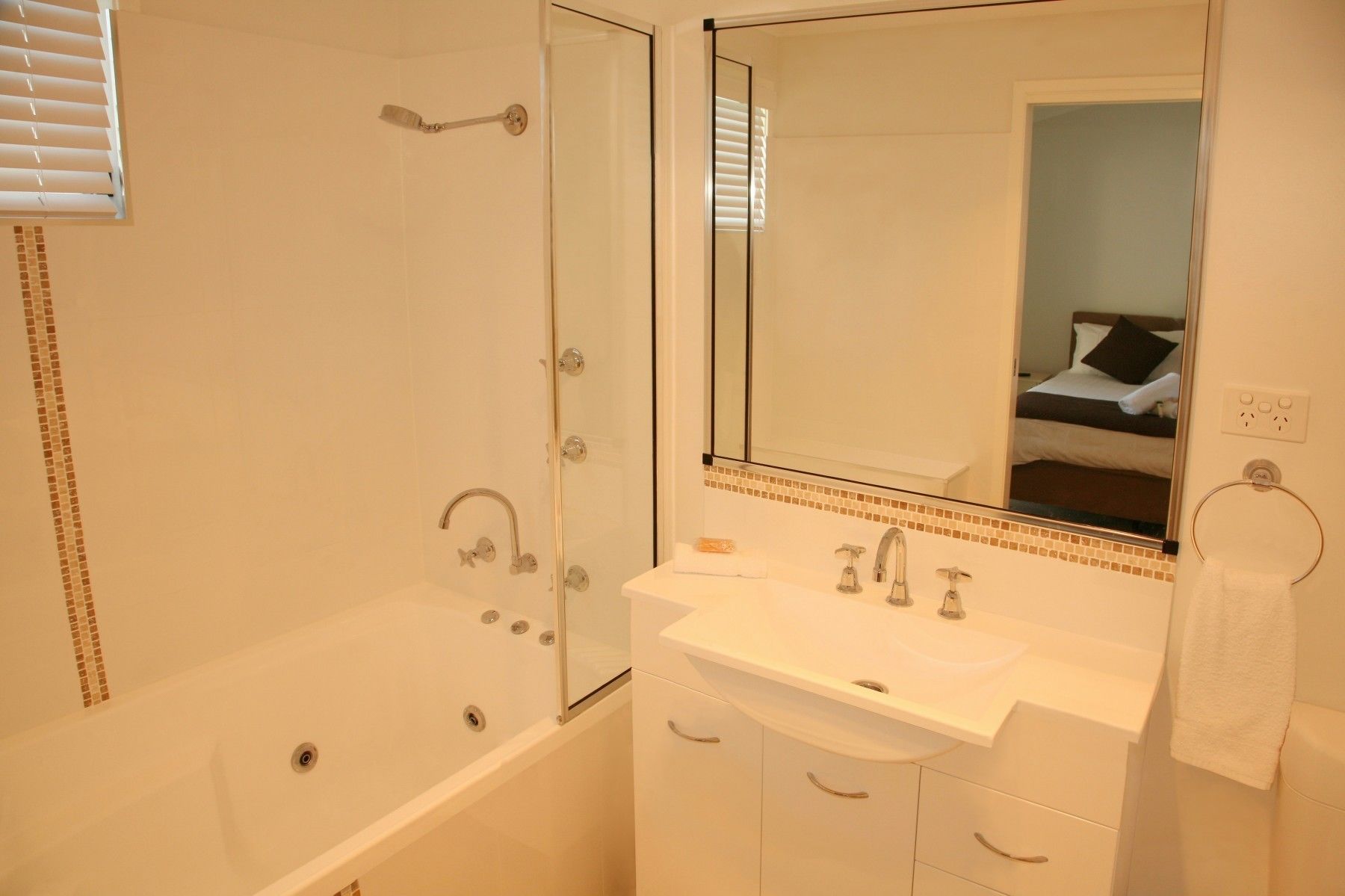 A bathroom with a bathtub, a sink, a mirror, and a shower.
