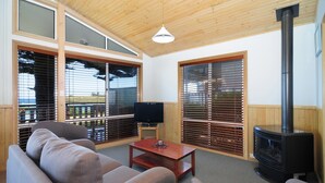 A cozy living room with a sofa, a coffee table, a TV, and a fireplace. - Surf Beach Holiday Park (Kiama)