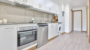 A modern kitchen with stainless steel appliances, white cabinetry, and a built-in washing machine.