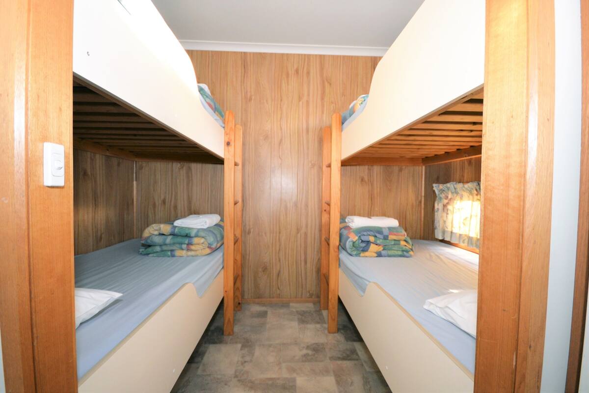 A bunk bed room with wooden walls and a tiled floor.
