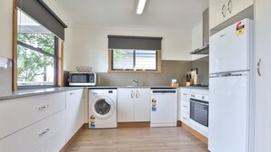 A modern kitchen with white cabinets, a built-in washing machine, a microwave, and a refrigerator.
