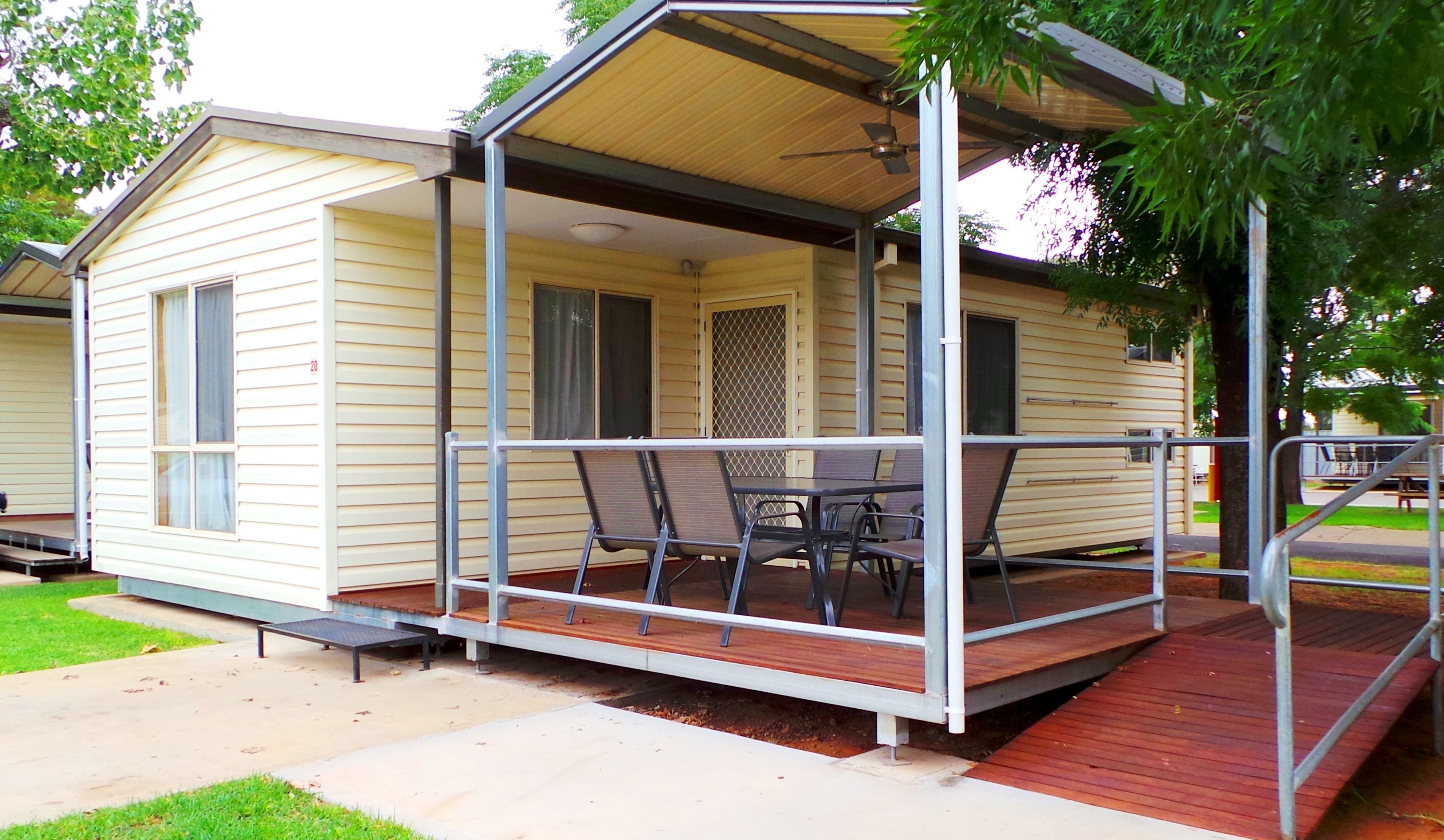 A small, single-story mobile home with a porch and a table with chairs.
