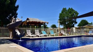 A swimming pool with lounge chairs and a thatched-roof structure.