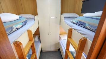 A compact cabin with two bunk beds, a wardrobe, and a small seating area.