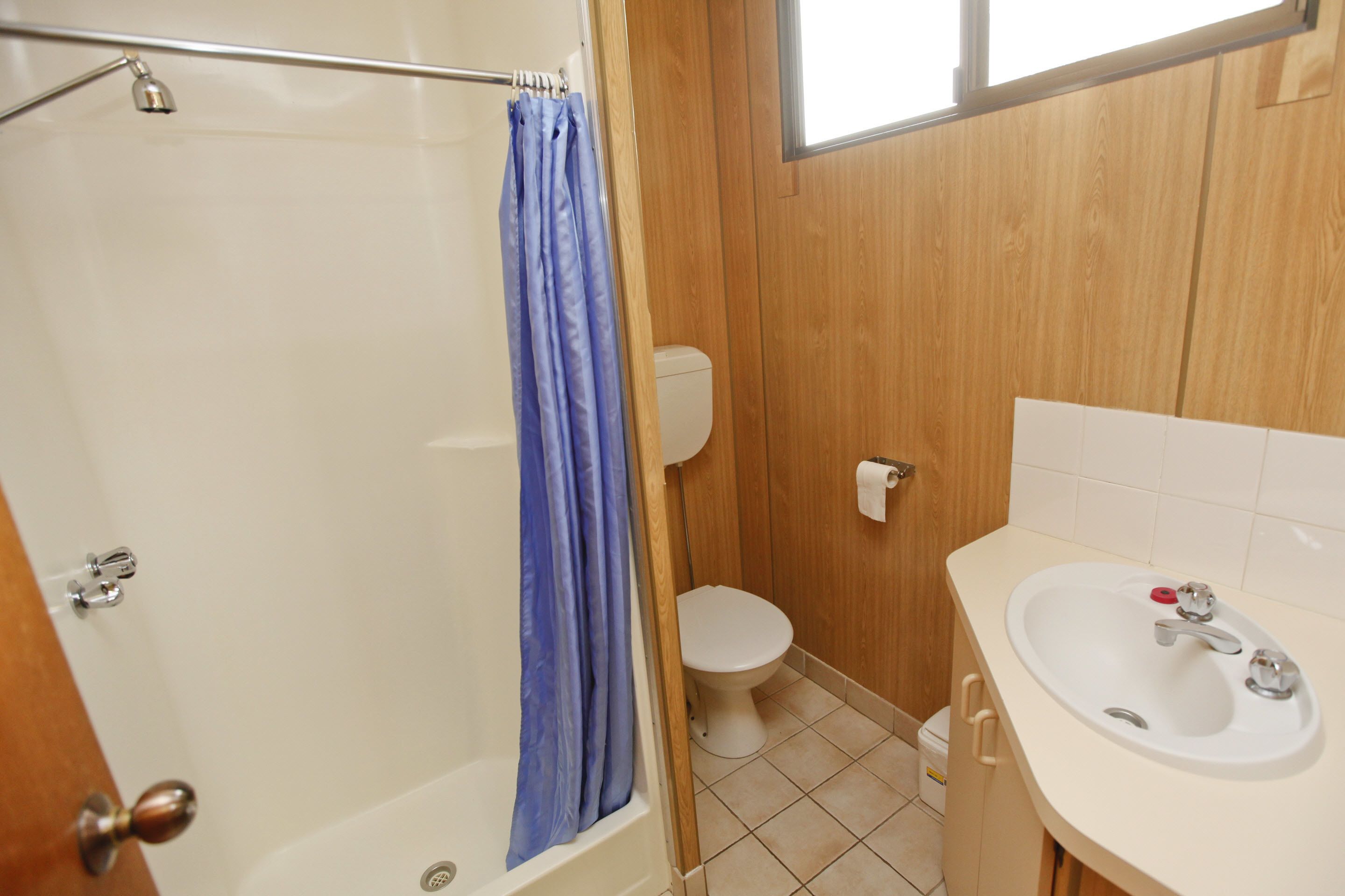 Une salle de bain avec douche, toilettes et lavabo.
