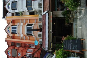 A building with a red and white facade, multiple windows, and a sign indicating a vacancy. - Karon Sunshine Guesthouse & Bar (Karon)