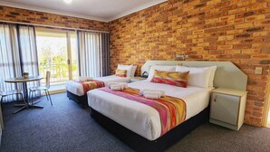 A hotel room with a brick wall, two beds, a small table, and a chair. - Golf Club Motor Inn Wingham (Wingham)