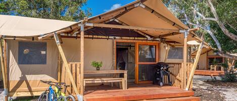 A wooden structure with a covered porch, a table, and a bench.
