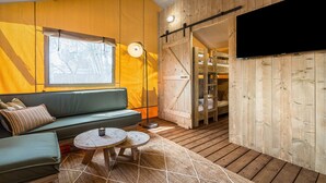 Una habitación acogedora con un sofá verde, una pequeña mesa redonda y un ventanal amplio.