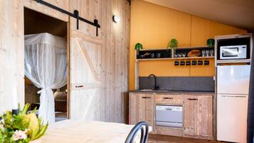 Una cocina compacta con armarios de madera, un microondas y un lavamanos.
