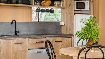 A kitchen with wooden cabinets, a dishwasher, a microwave, and a window with hanging pots.