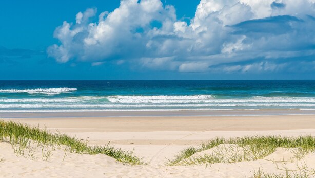 Una playa con cielos despejados y olas.