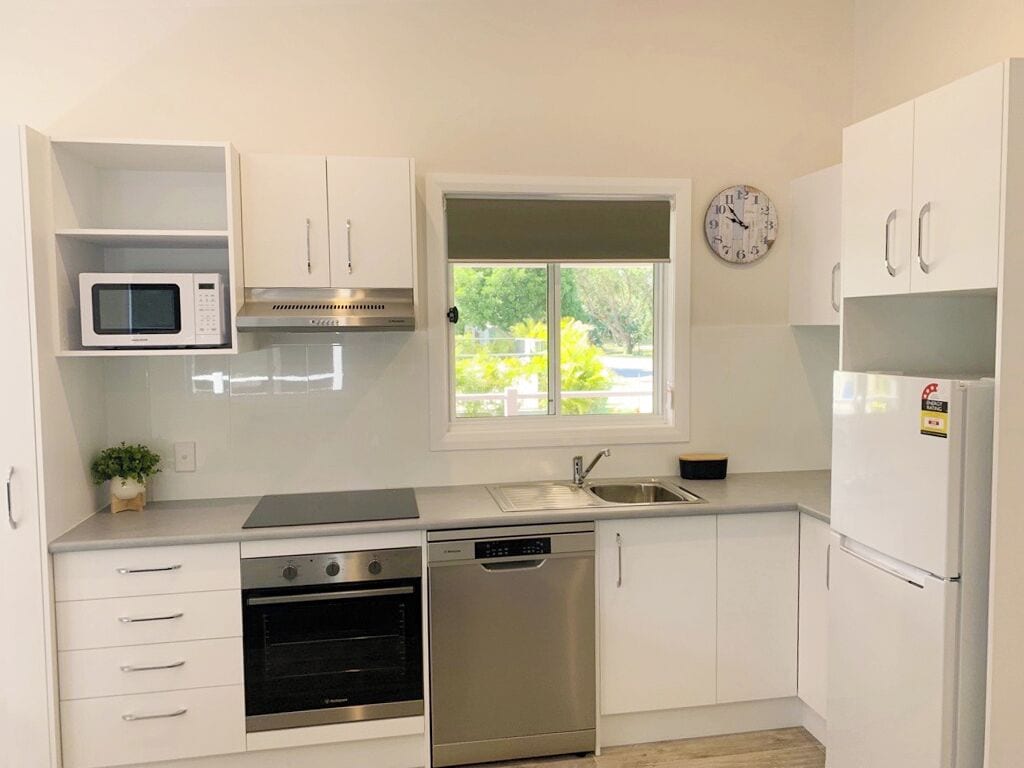 A modern kitchen with white cabinets, a microwave, a stove, a dishwasher, and a refrigerator.
