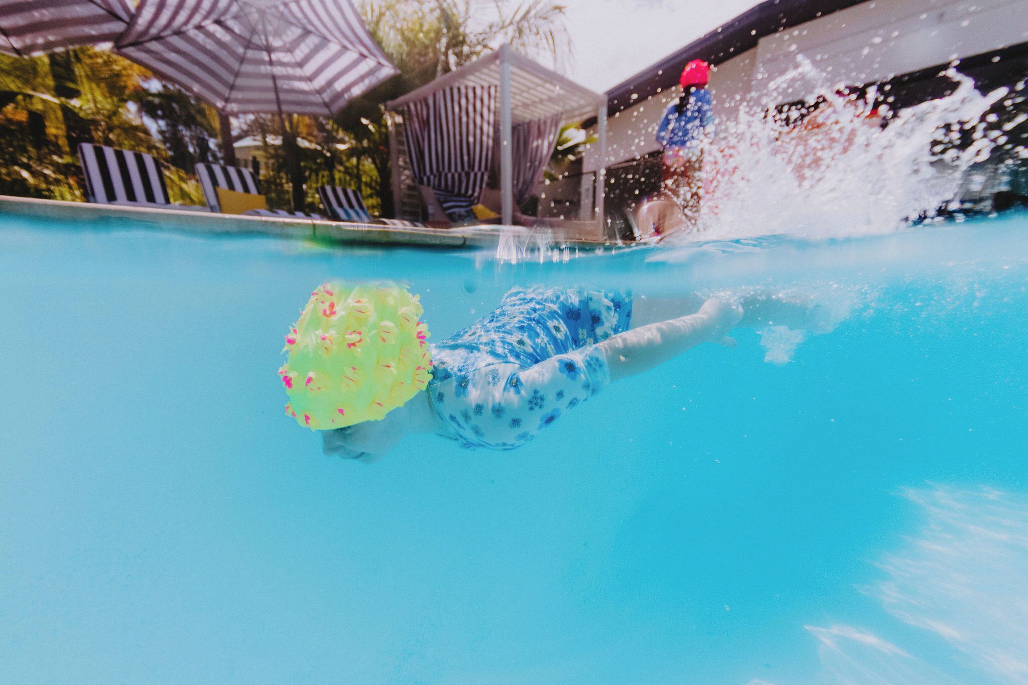 A swimming pool with a person swimming and another person in the water.