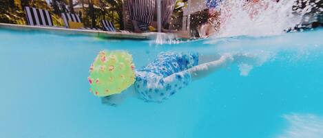 A swimming pool with a person swimming and another person in the water.