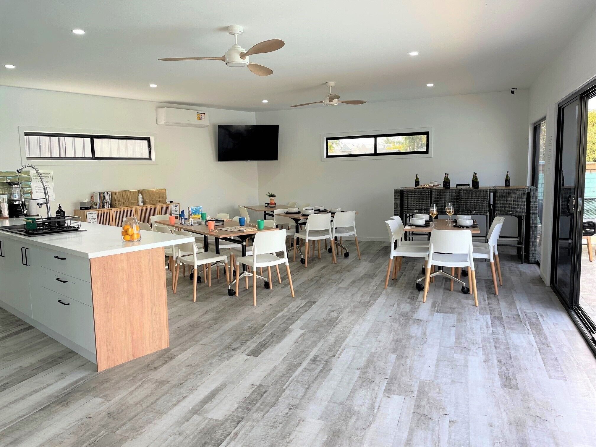 A modern kitchen with a central island, white chairs, and a dining area with a table and chairs.