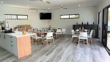 A modern kitchen with a central island, white chairs, and a dining area with a table and chairs.