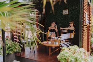 Un área de estar al aire libre con muebles de madera y una mesa con un cuenco de vidrio.