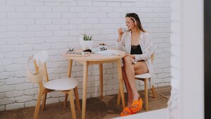 A person sitting at a round wooden table with a white brick wall in the background.