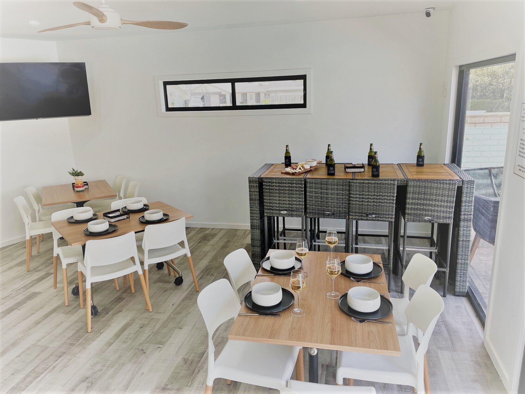 A dining area with a wooden table, white chairs, and a television mounted on the wall.