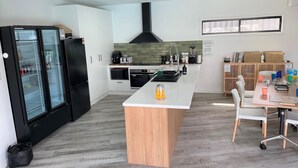 A modern kitchen with a central island, black refrigerator, and a dining area with chairs.
