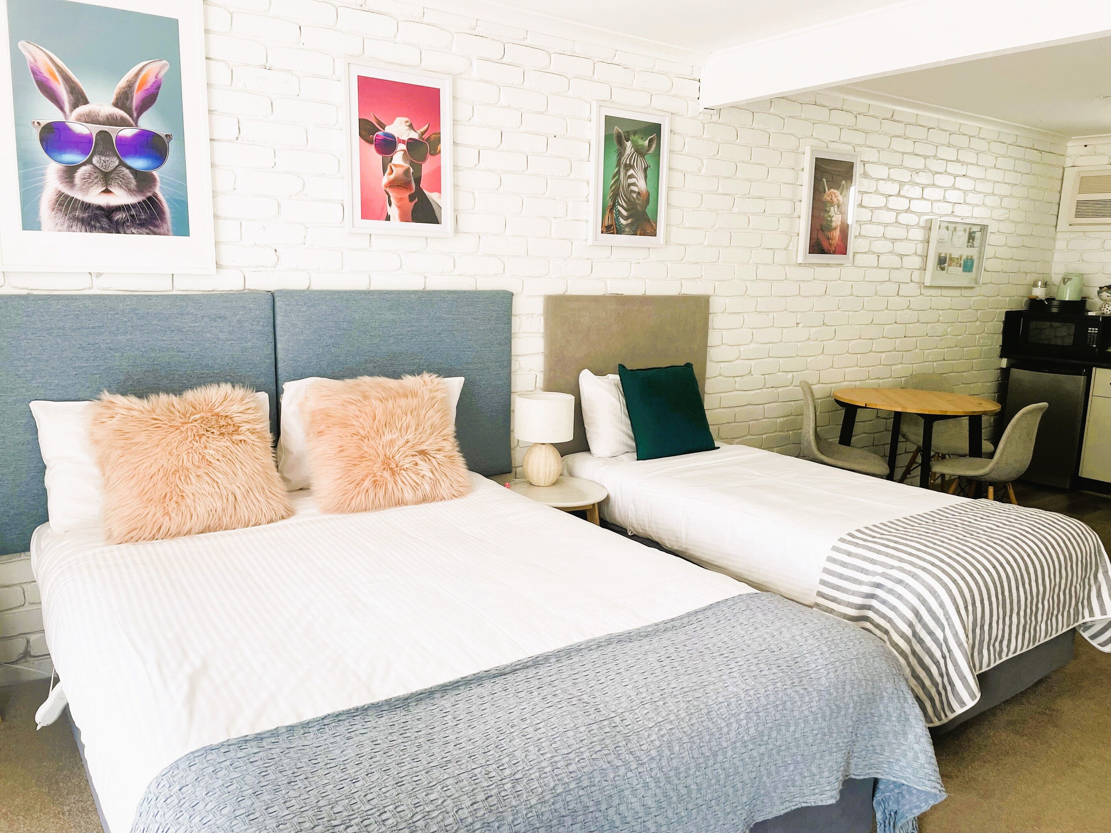 A hotel room with two beds, a small table, a chair, and a microwave.