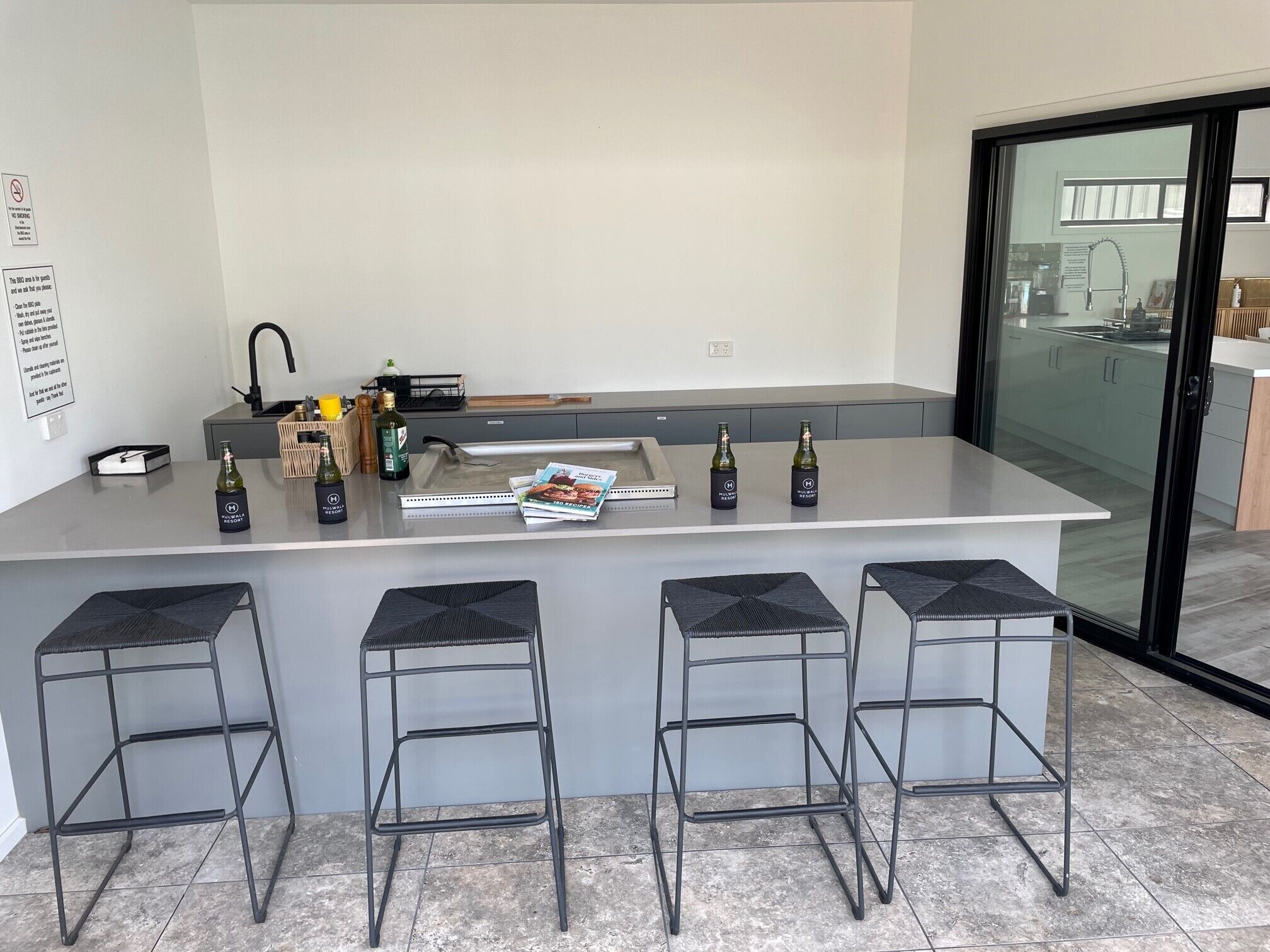 A modern kitchen with a central island, bar stools, and a glass door leading to a balcony.