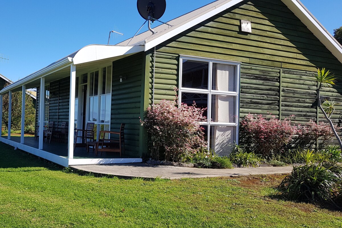 A row of log cabins with attached porches, each featuring a window and a door.