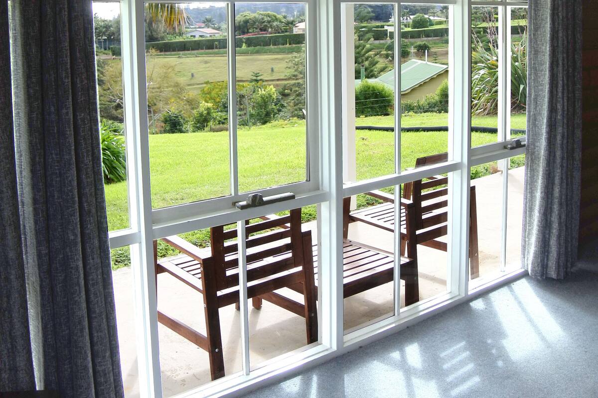 A room with a large sliding glass door leading to an outdoor patio with a wooden bench.