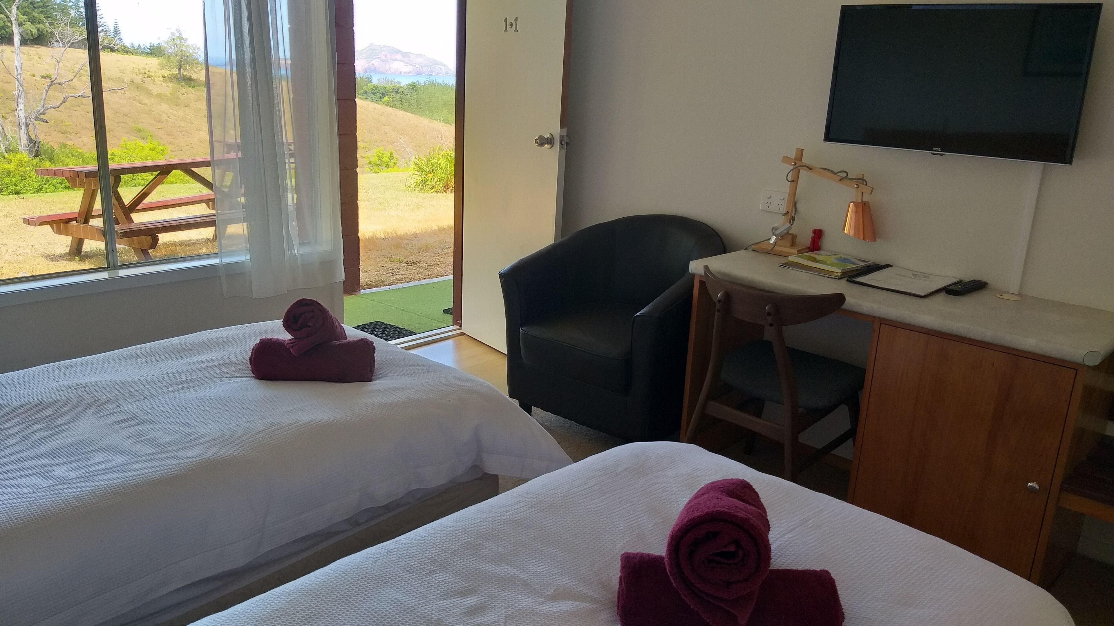 Habitación de hotel con dos camas, un escritorio, una silla, un televisor y vistas al exterior.