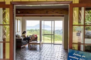 A cozy room with a large sliding glass door leading to a scenic view of hills and a body of water.