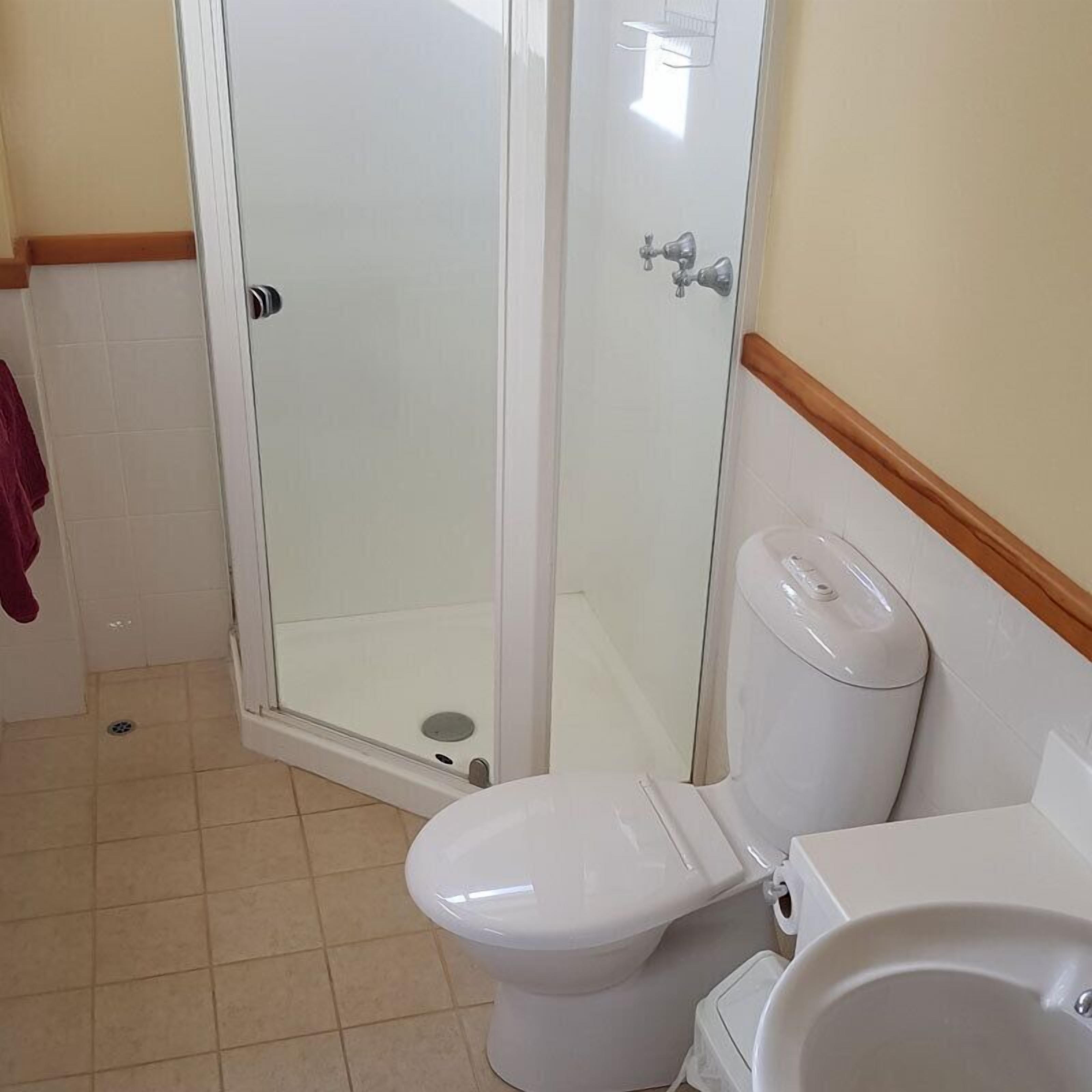 A bathroom with a toilet, a sink, and a glass-enclosed shower.