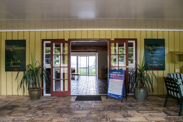 A hotel entrance with a reception desk, a sign for Boutique Accommodation, and a sign for a restaurant and BBQ.