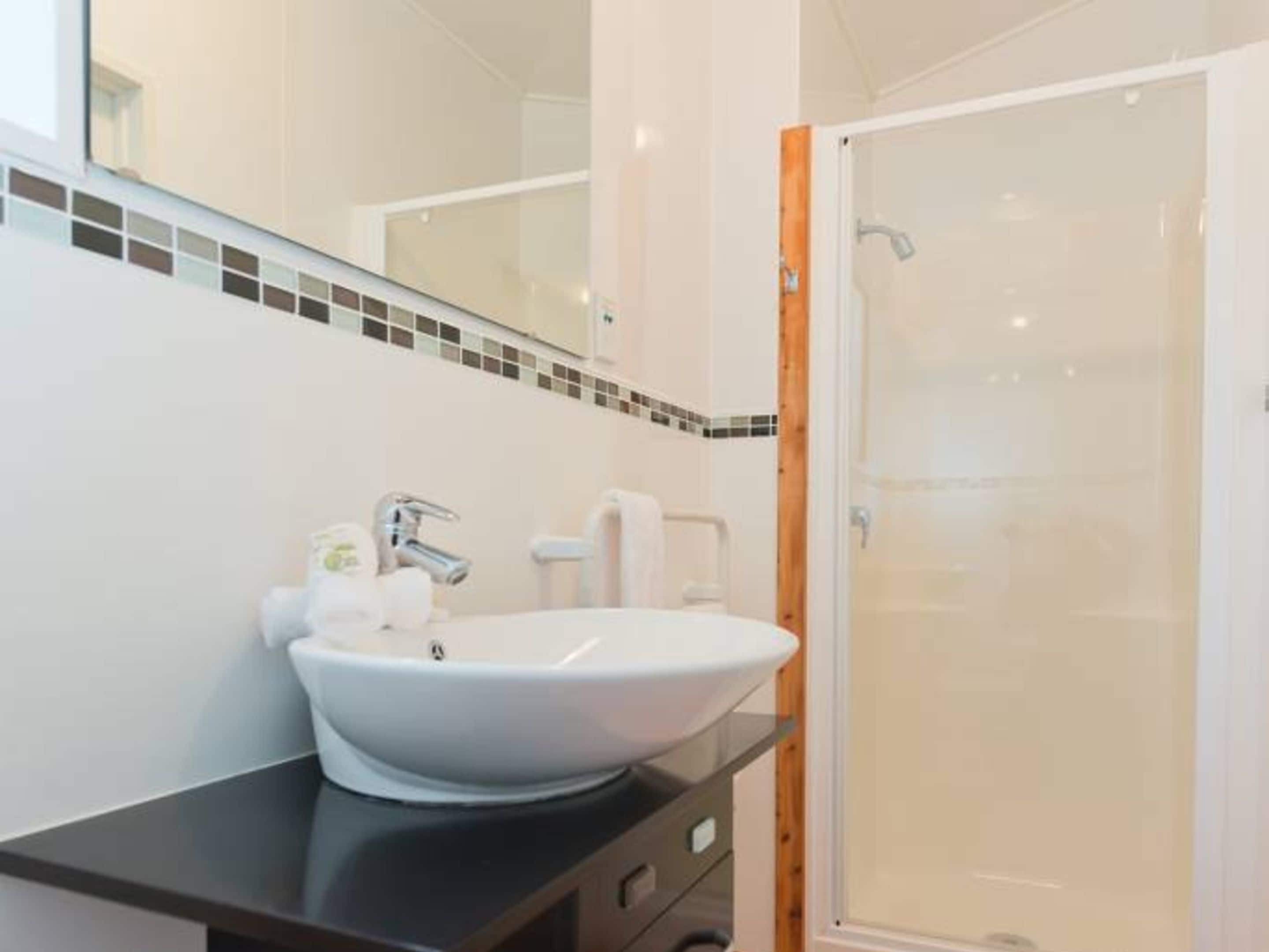 A bathroom with a white sink, a mirror, and a shower.