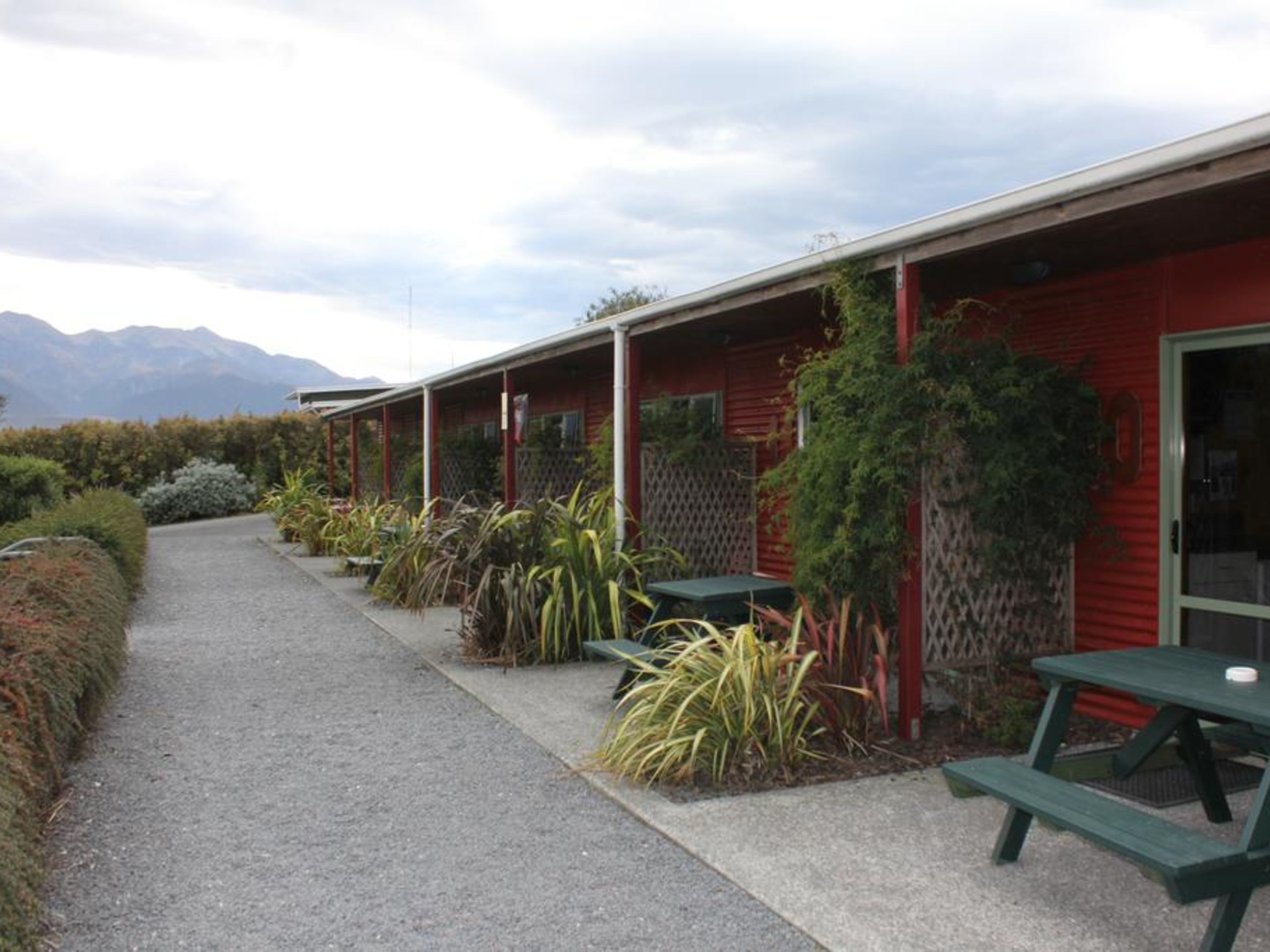 A row of red buildings with outdoor seating and a gravel path.