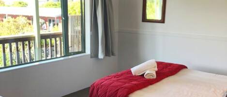 Habitación de hotel con dos camas, un ventanal con vistas al exterior y un pequeño marco de fotos en la pared.