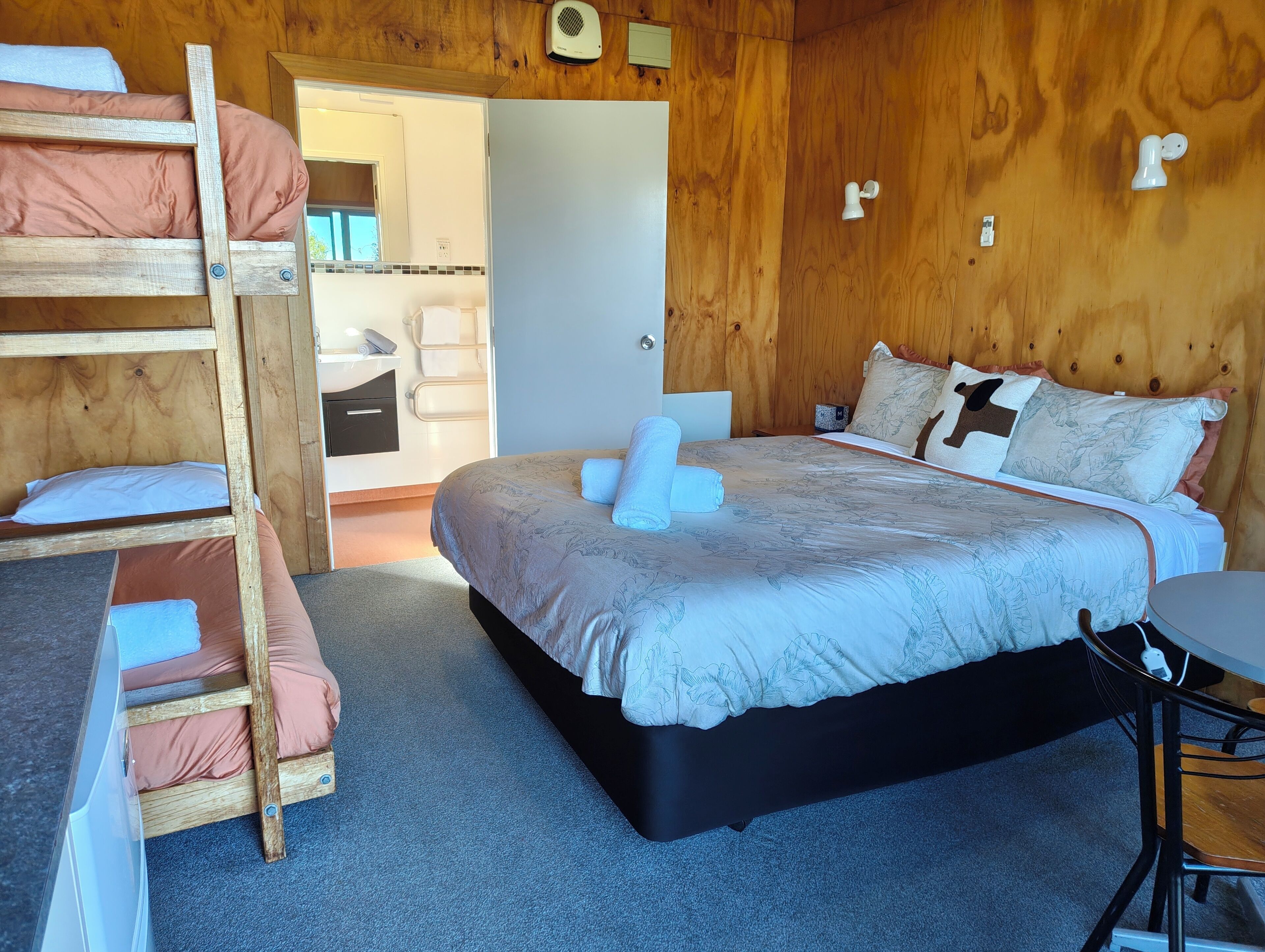 A cozy room with a bunk bed, a single bed with floral bedding, and a small table.