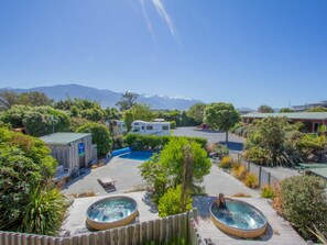 Un resort con piscina, jacuzzis y vistas a montañas.