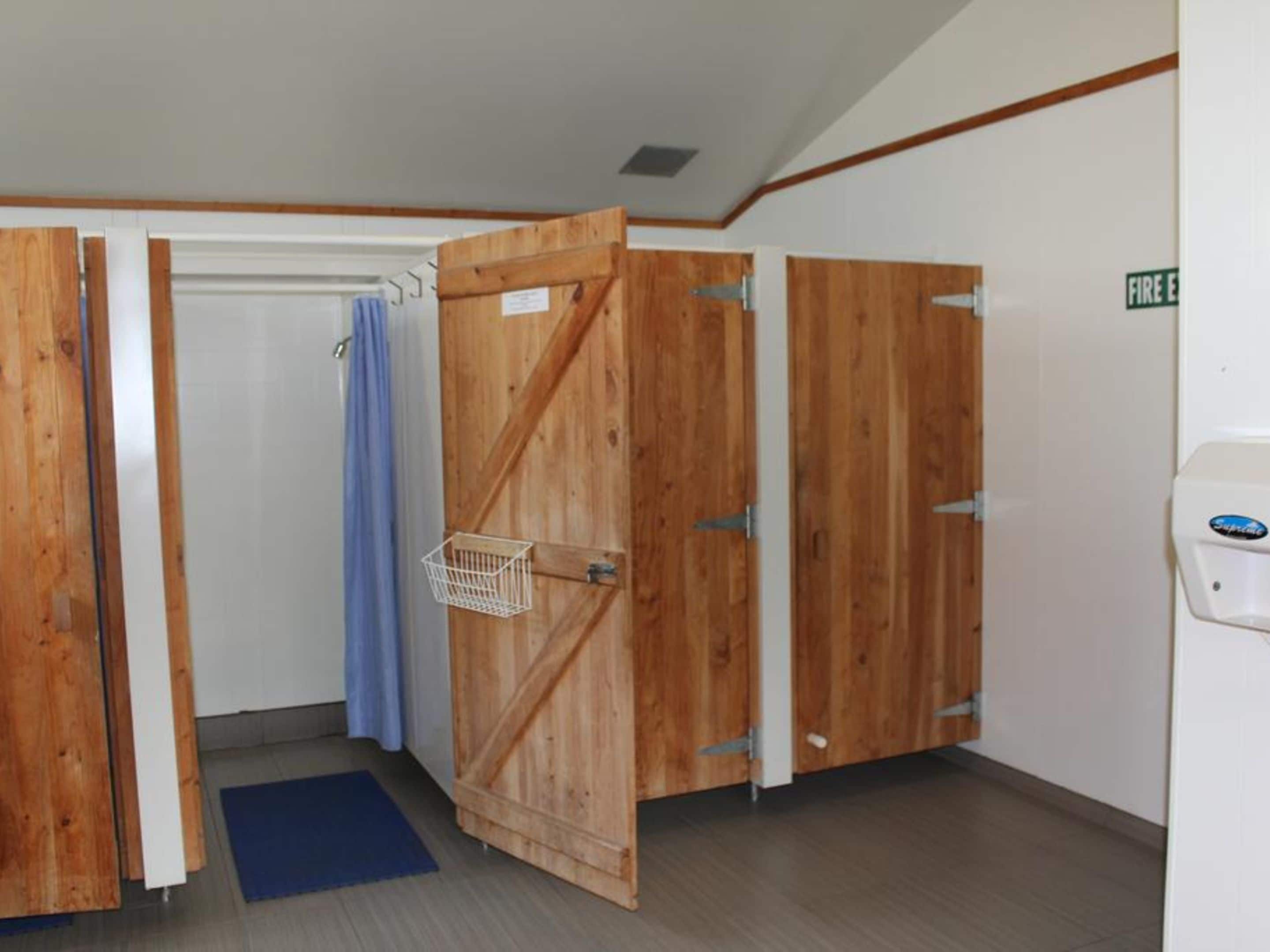 Una habitación con puertas de madera, una cortina azul y un lavamanos blanco.