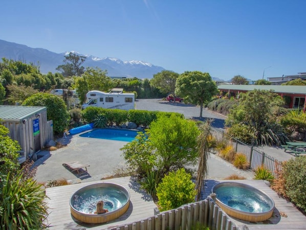 Zona residencial con piscina, jacuzzis y una caravana estacionada al fondo.