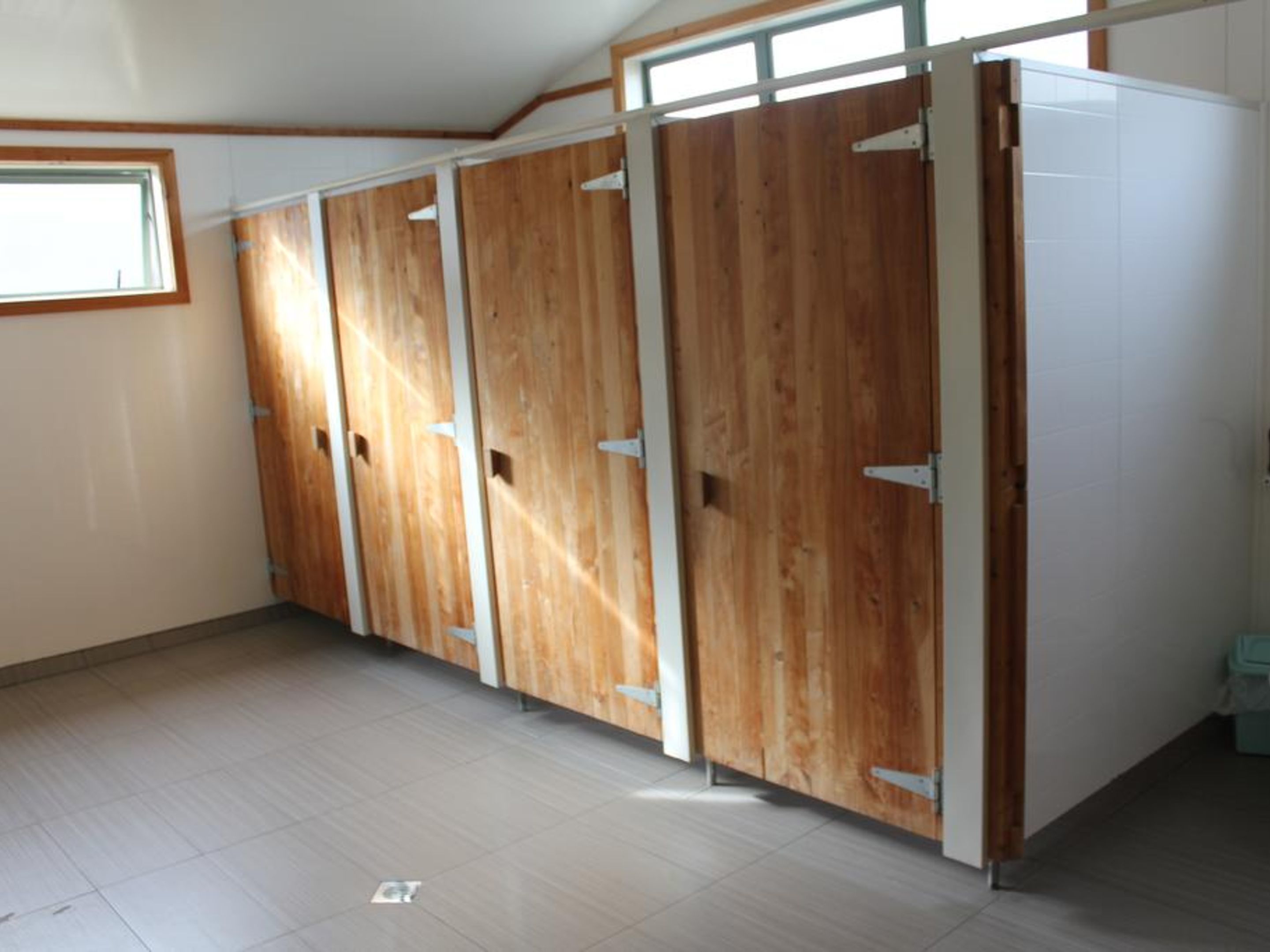 A room with four wooden doors, a tiled floor, and a window.