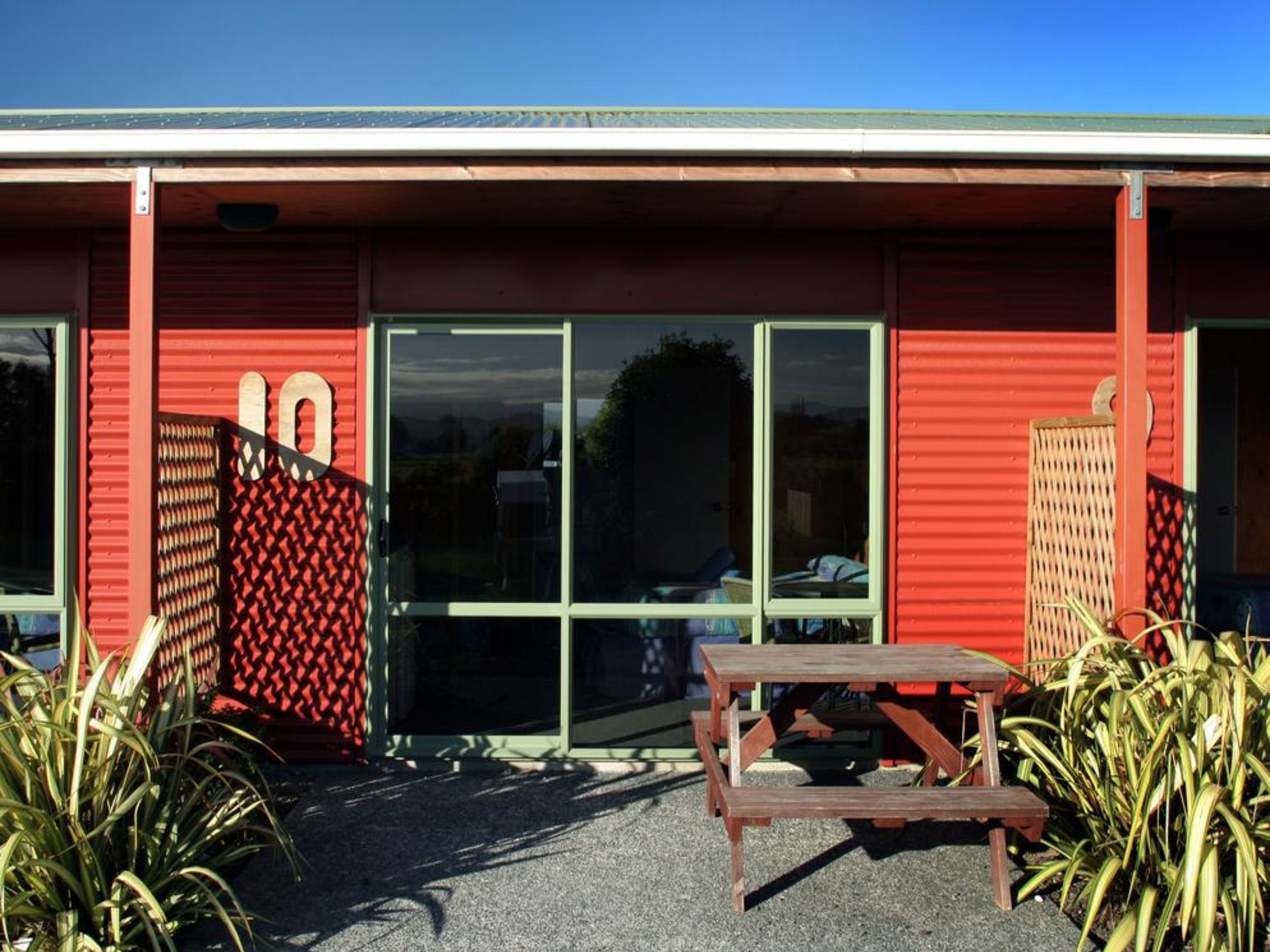 A red building with a large number '10' sign, a glass door entrance, and a wooden bench outside.