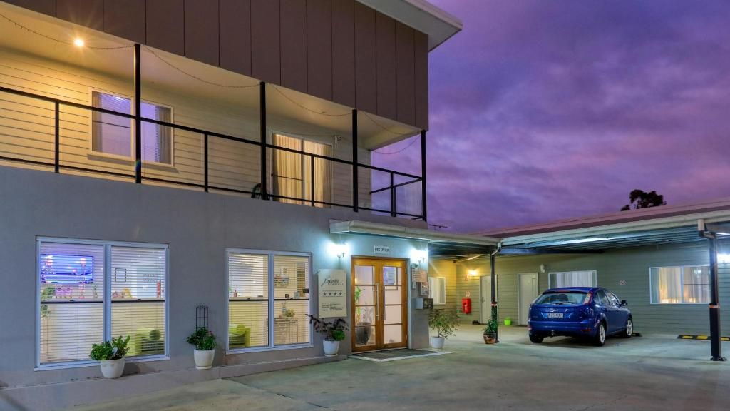 A two-story building with a covered parking area and a blue car parked inside.