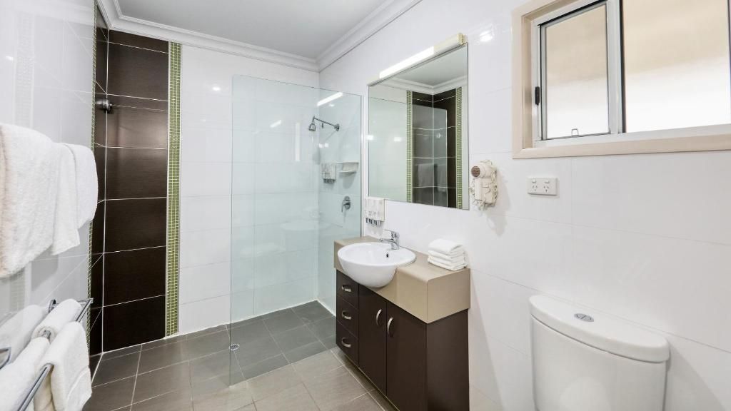 A modern bathroom with a glass shower enclosure, a white sink, and a vanity with a mirror.