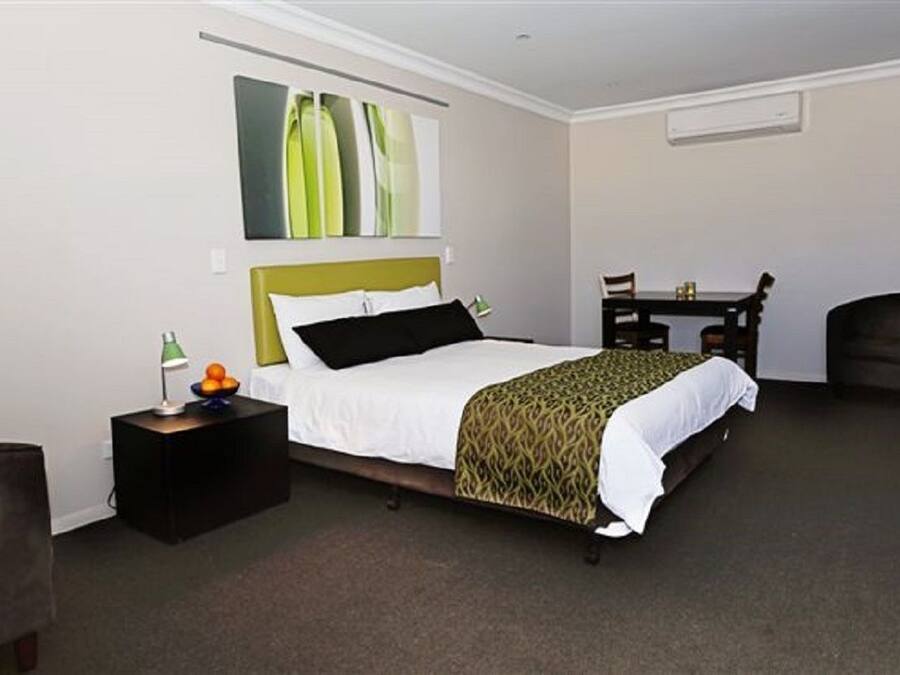 A hotel room with a bed, bedside table, lamp, and a small table with chairs.