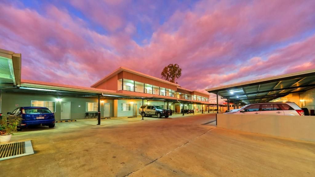 A hotel with a covered parking area and multiple cars parked.