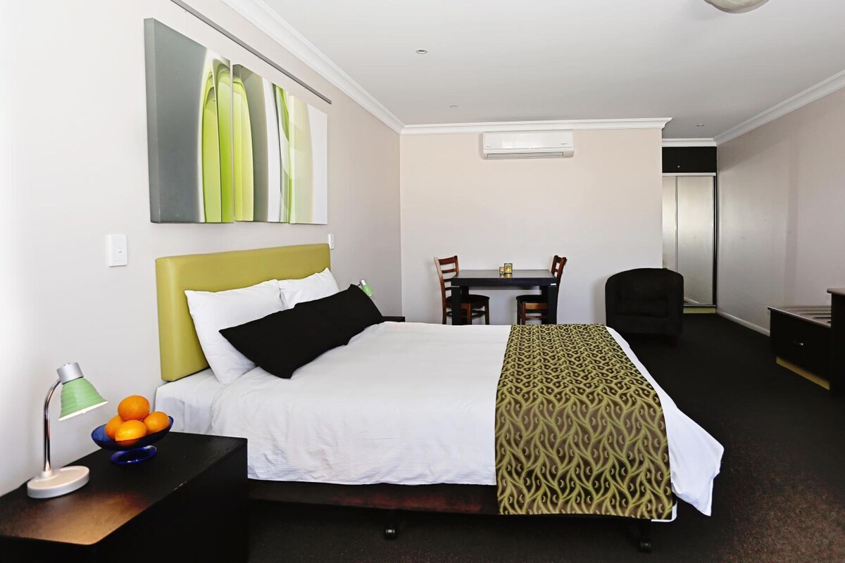 Una habitación de hotel con cama, escritorio, silla y mesa de comedor.