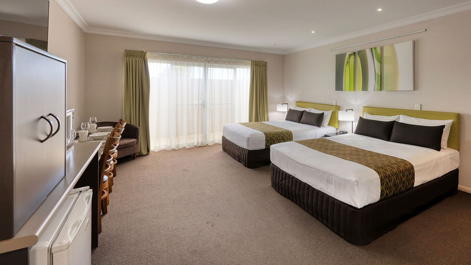 A hotel room with two beds, a desk, and a minibar.